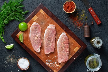 wooden cutting board with three pieces of pork