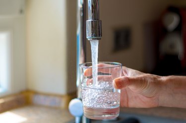 Cropped Hand Filling Glass With Water From Faucet