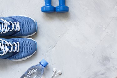 Flat lay sport shoes, bottle of water, dumbbells and earphones
