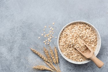 Rolled oats, oat flakes in bowl on concrete background