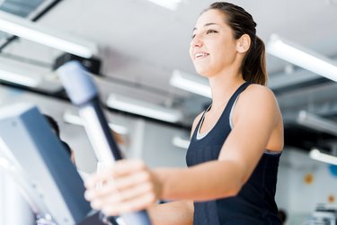 Beautiful young lady using the elliptical trainer