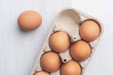 fresh eggs in paper tray on white surface b