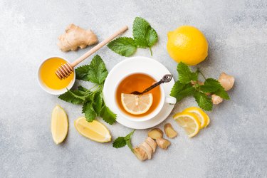 White Cup with natural herbal tea ginger lemon mint and honey. Gray background Copy space.