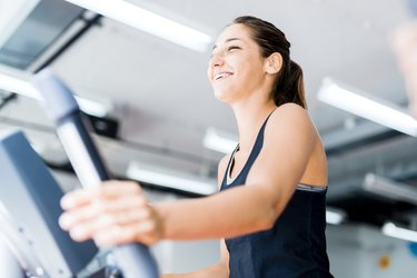 Beautiful young lady using the elliptical trainer