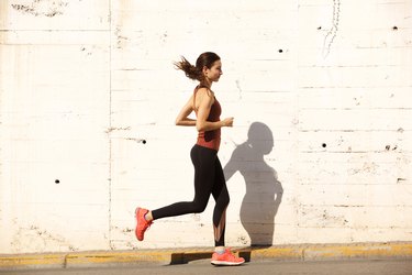 Side portrait of fit young woman running outdoors