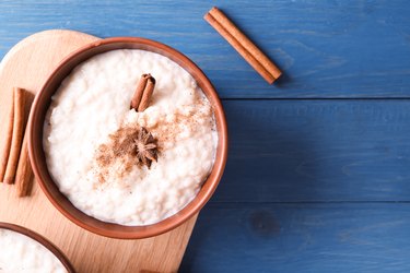 Delicious rice pudding with cinnamon and anise in bowl on wooden table