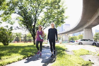 Women walking on sunny, urban path