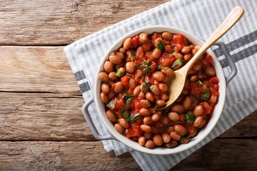 Stewed gluten-free beans or borlotti in tomato sauce with herbs close-up in a bowl. horizontal top view from above