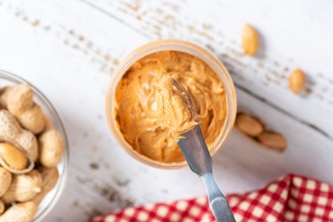 Close up, Creamy and smooth crunchy peanut butter on knife, Top view. Natural nutrition and organic food.