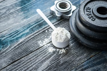 Classic dumbbell with pre workout powder on rustic wooden table