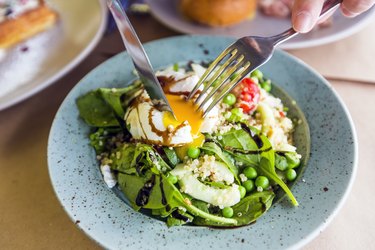 Close up of healthy salad with quinoa, green peas, spinach and poached egg