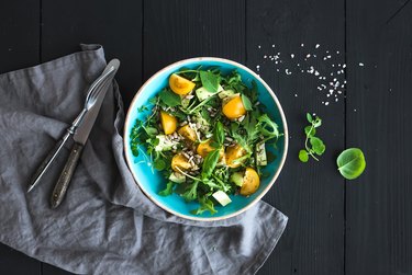 Bowl of green salad with avocado, arugula, cherry tomatoes and sunflower seeds