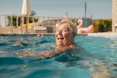 person burning calories treading water in her backyard pool during summer