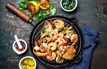 Grilled shrimps prawns on vintage grill pan, top view. Dark background