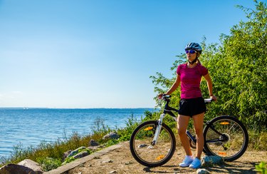 Woman cycling for exercise on trail near ocean