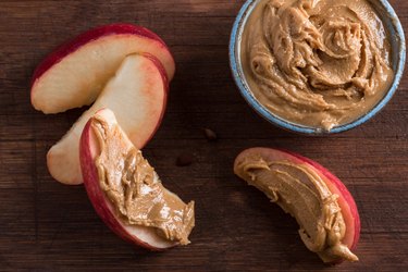 Close-Up Of Apple Slices With Peanut Butter On Table