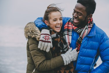 Young Couple Laughing On A Winter Beach and Being Thankful