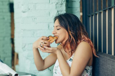 Woman eating croissant in coffee shop