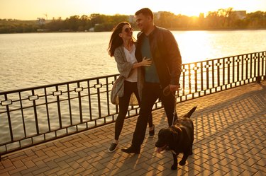 Full length of a happy couple walking dog