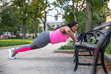 woman doing incline push-ups outdoors on a bench as part of a full-body workout