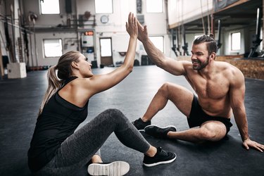 Two fit young people high fiving together after a workout