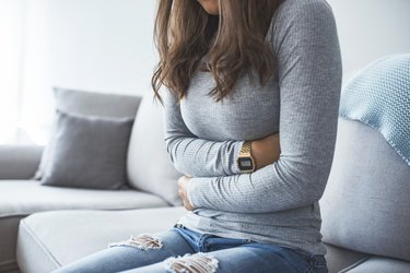 Woman sitting on the sofa feeling full and bloated after eating
