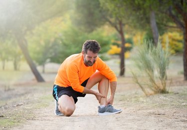 Athletic runner male holding leg with muscle cramp due to potassium deficiency