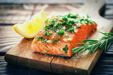 High-protein salmon fillet with herbs and lemon on wooden cutting board