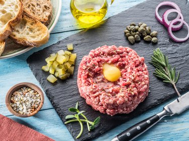 Steak tartare served with raw quail egg yolk, capers and bread. Meat dish.