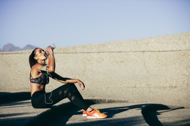 Healthy woman drinking water after exercising