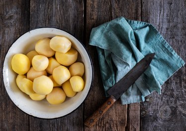 Directly Above Shot Of Peeled Boiled Potatoes In Bowl By Napkin And Knife On Table