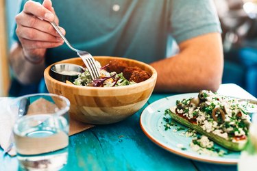 An unrecognizable man eating a big bowl of volumetrics diet foods