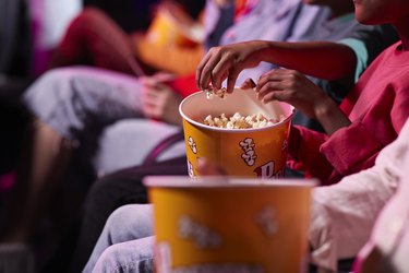Friends sharing movie theater popcorn with butter