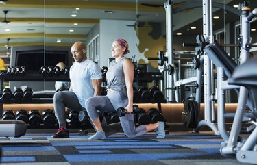 Hispanic couple working out at the gym, doing lunges