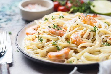 Close view of a plate of spaghetti with shrimp and parsley