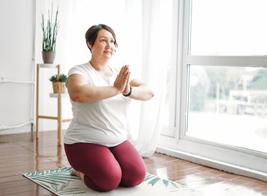 Adult charming brunette woman plus size body positive practice yoga at the bright studio