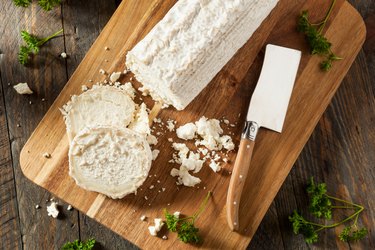 Raw white organic goat cheese on a cutting board.