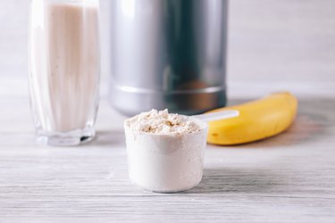 Scoop with whey protein powder, banana and glass