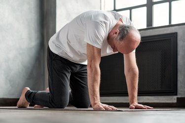 older man doing cat cow yoga pose, as a natural remedy for headaches
