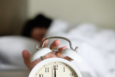 Cropped Hand Of Person Turning Off Alarm Clock in the morning, as a natural remedy for insomnia