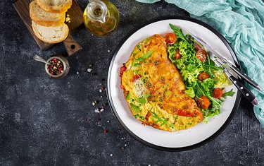 Breakfast. Omelette with tomatoes, avocado, blue cheese and green peas on white plate.  Frittata - italian omelet. Top view