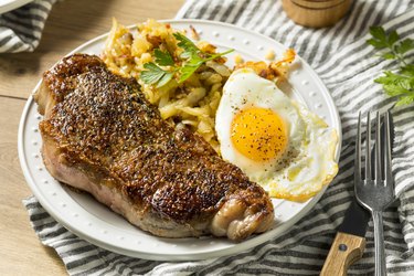 A plate of homemade breakfast, including steak, eggs and potatoes