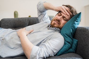 Guy feeling unwell with a stomach ache while sitting at home