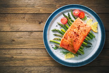 Grilled salmon garnished with green asparagus and tomatoes
