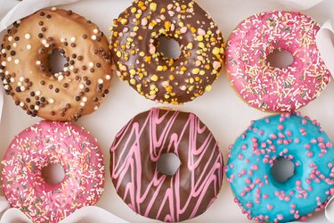 Top view of colorful doughnuts decorated with sprinkles and icing in a box