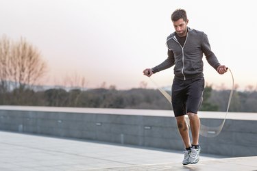 Person in athletic clothes jumping rope outside to increase running endurance.