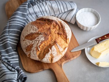 Loaf bread on a chopping board with butter