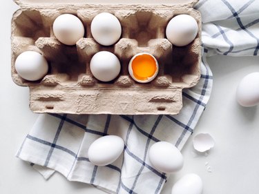 White eggs in carton with dish towel