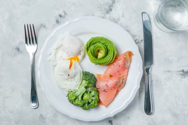 Top view of a plate with keto diet food, including salmon, eggs and avocado