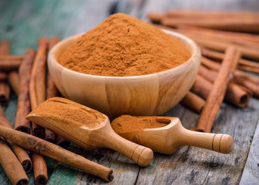 Close-Up Of Cinnamons With Grounded Spice On Table